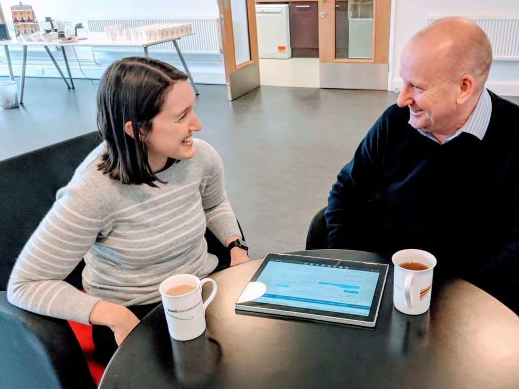 Two people sat at a table with hot drinks and a tablet showing the Xero accountancy package. - Wessex Commercial Solutions Xero Accountants in Exeter and Yeovil